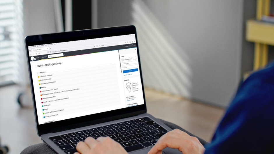 Ein aufgeklappter Laptop, Hände berühren die Tastatur. Auf dem Bildschirm ist eine Webseite mit der Überschrift "GRIPS - Uni Regensburg" zu sehen.
