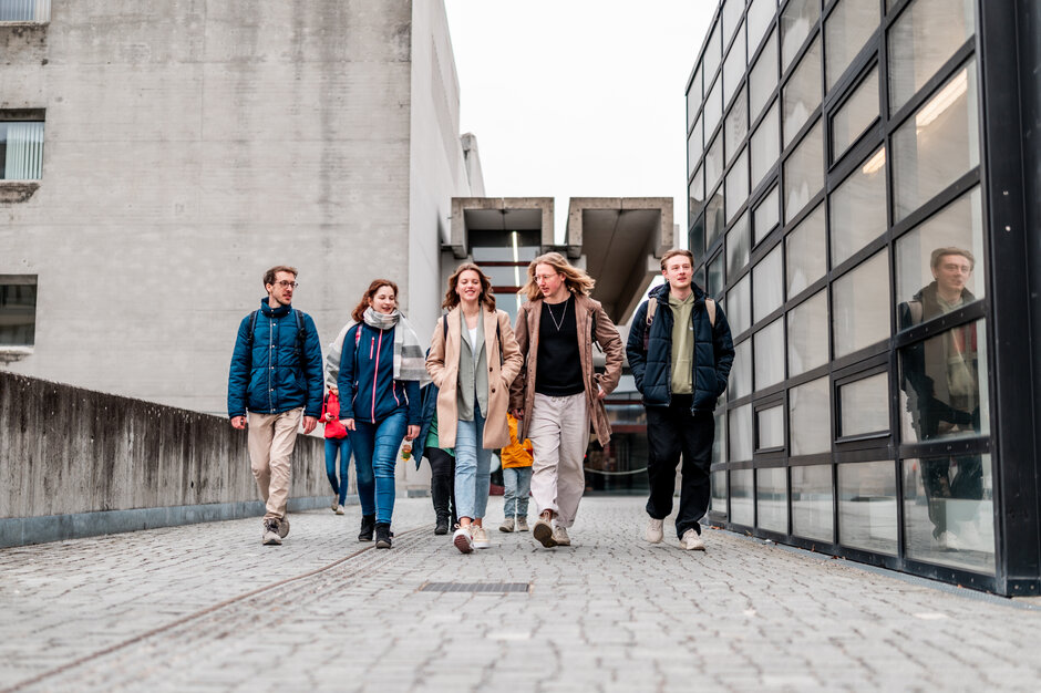 Eine Gruppe von Studierenden gehen über den Campus der Universität Regensburg.