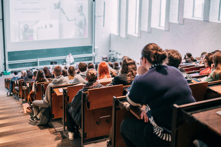 Vorlesung in einem gut besuchten Hörsaal mit Tageslicht im Gebäudeteil Recht und Wirtschaft (öffnet Vergrößerung des Bildes)