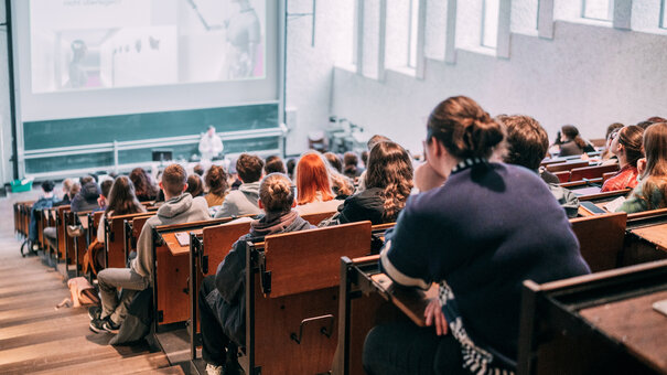 Vorlesung in einem gut besuchten Hörsaal mit Tageslicht im Gebäudeteil Recht und Wirtschaft