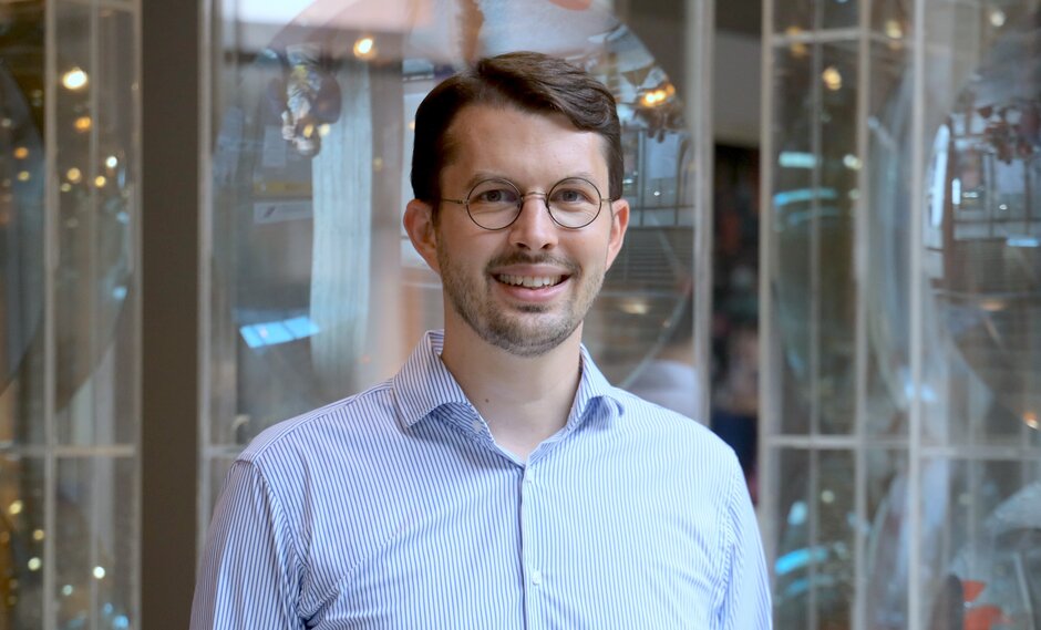 Prof. Dr. Matthias Widbiller im Porträt vor einem verschwommenen Hintergrund. Er trägt ein helles Hemd, eine Brille, hat kurze braune Haaare und ist um die 40 Jahre alt.