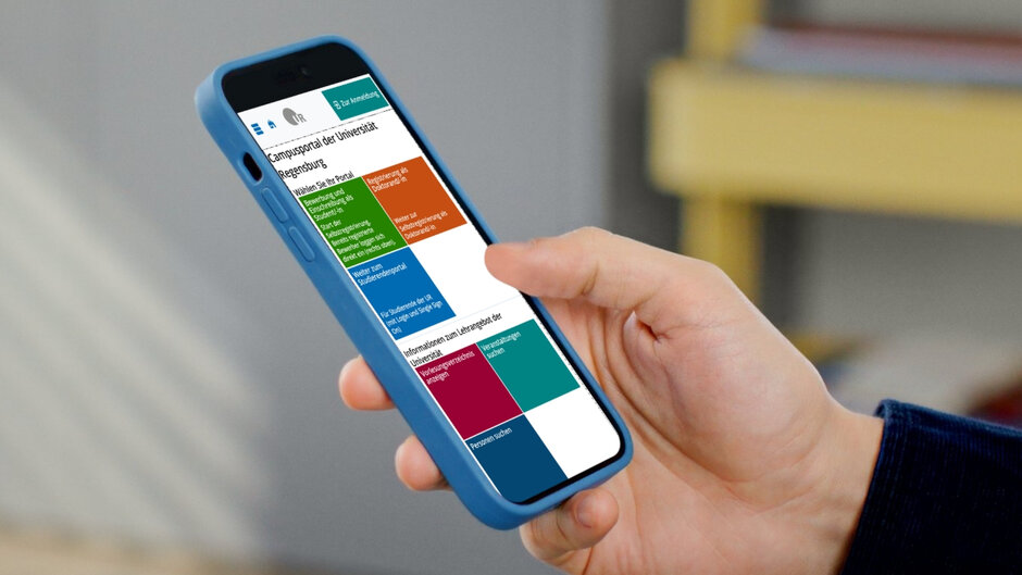 Eine Hand hält ein Smartphone mit blauer Hülle. Auf dem Display ist die Startseite des Studierendenportals zu sehen.