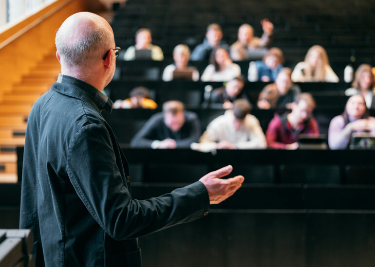 Ein Dozent hält in einem Hörsaal einen Vortrag vor Studierenden.
